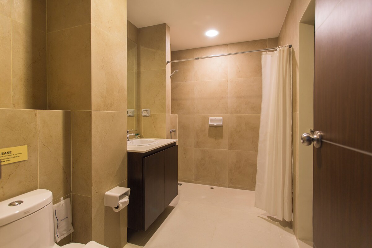 A bathroom with a toilet, sink, and shower area.