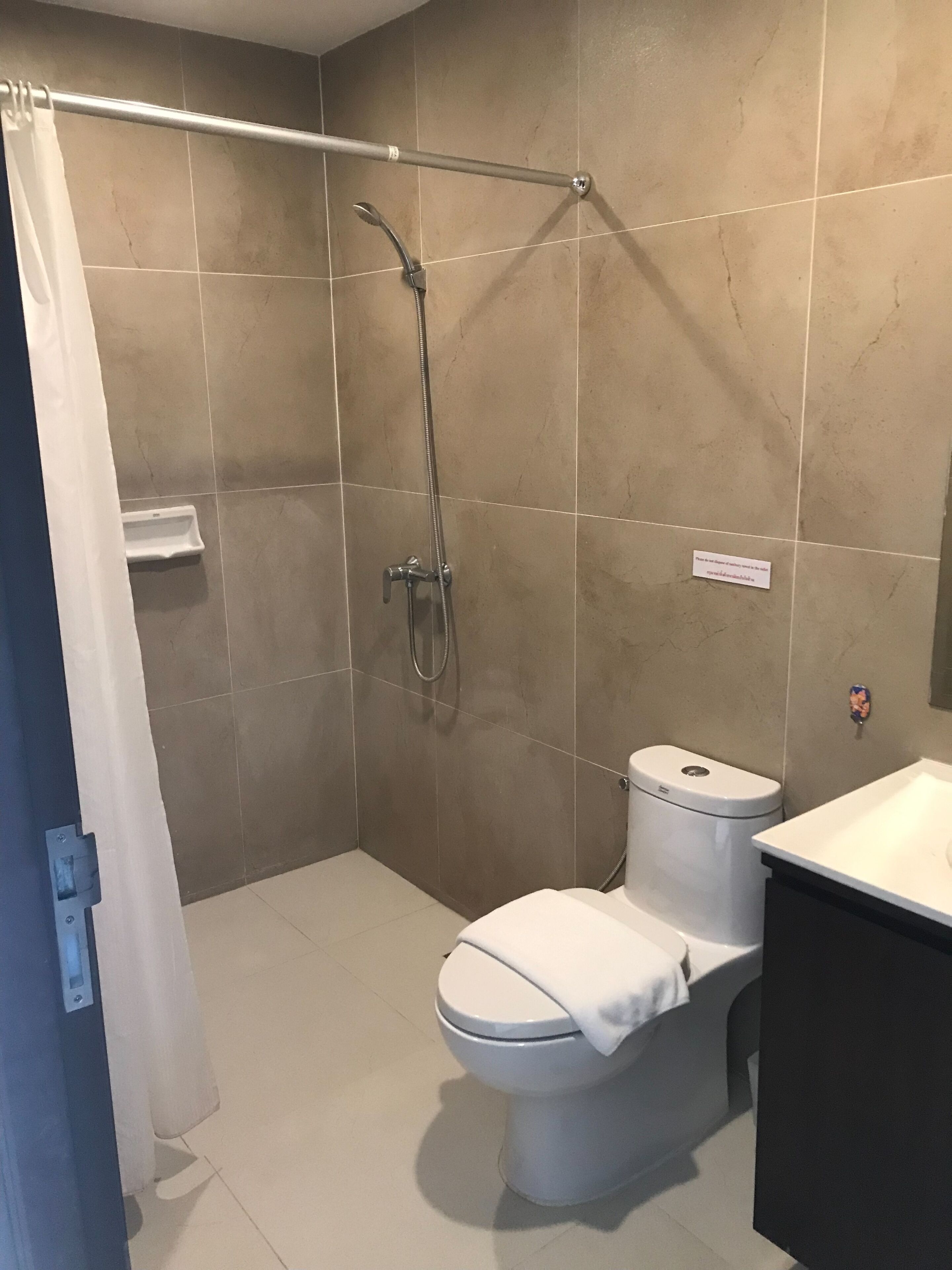Een badkamer met douche, toilet en wastafel.