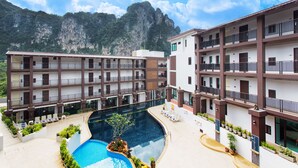 A hotel with multiple floors, a swimming pool, and a mountainous backdrop. - The Lai Thai Luxury Condominiums (Krabi)