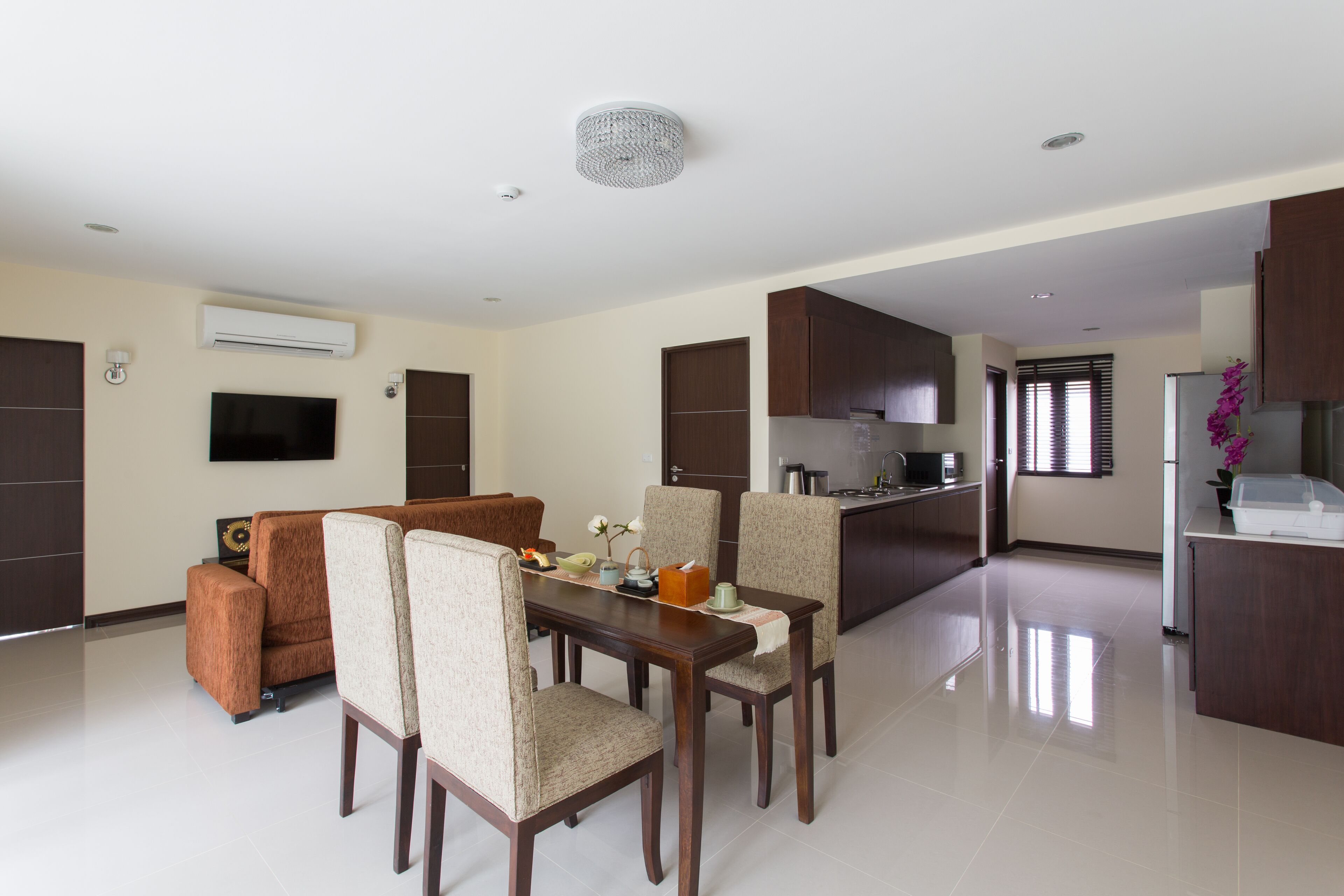 Una sala moderna con comedor, cocina y televisor montado en la pared.