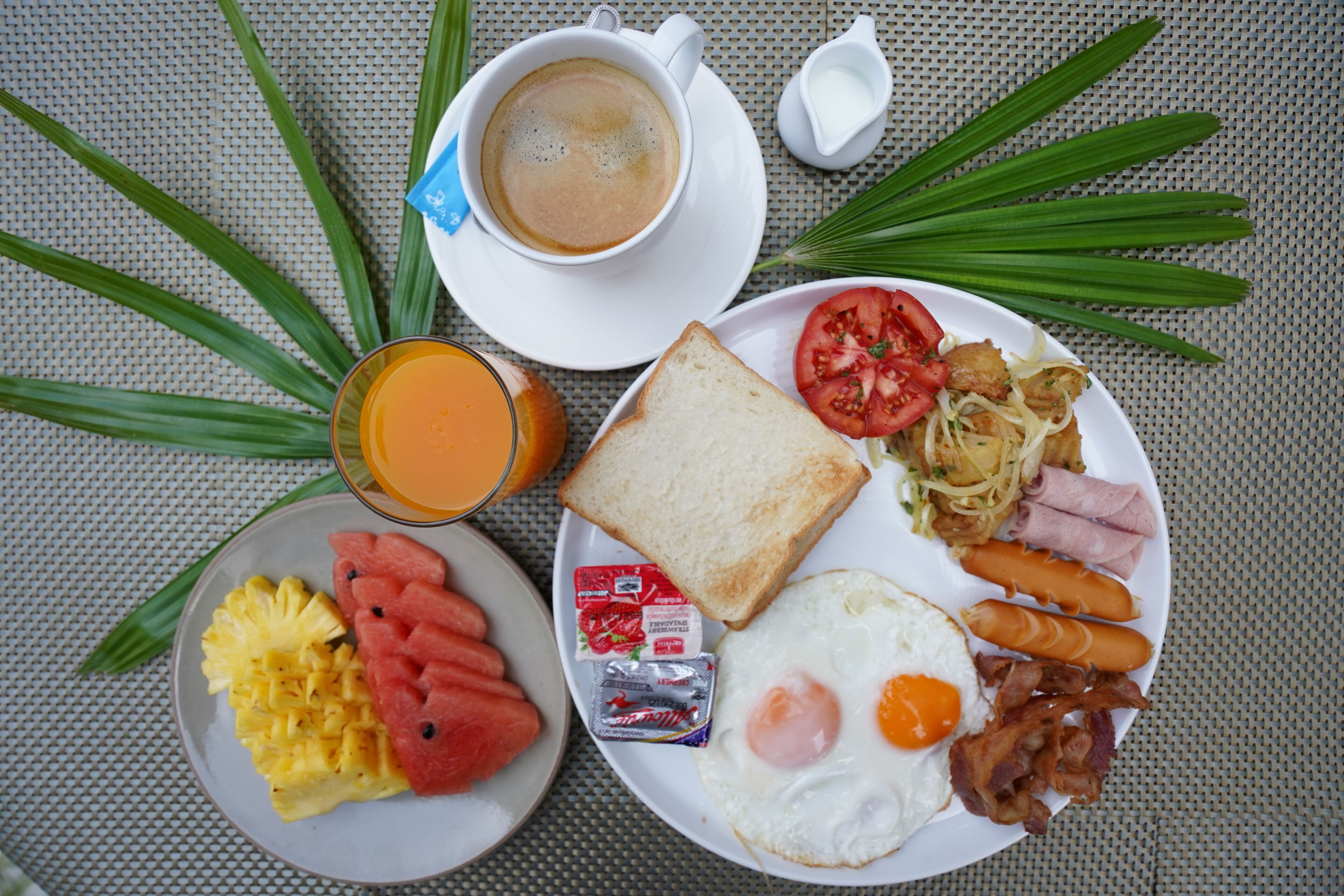 A breakfast plate with toast, eggs, bacon, tomatoes, and sausages.