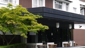 A modern building with a covered outdoor seating area, a tree, and a staircase leading to the entrance. - Tsukagoshiyashichibee (Shibukawa)