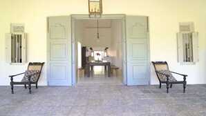 An open doorway leading to a dining area with a table and chairs, a hanging lantern, and a stone floor.