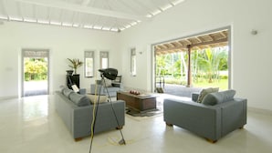 A spacious living room with two grey sofas, a coffee table, and a tripod with a camera.