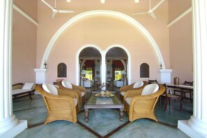 A spacious lobby with a high ceiling, two large arched doorways, and a central coffee table.