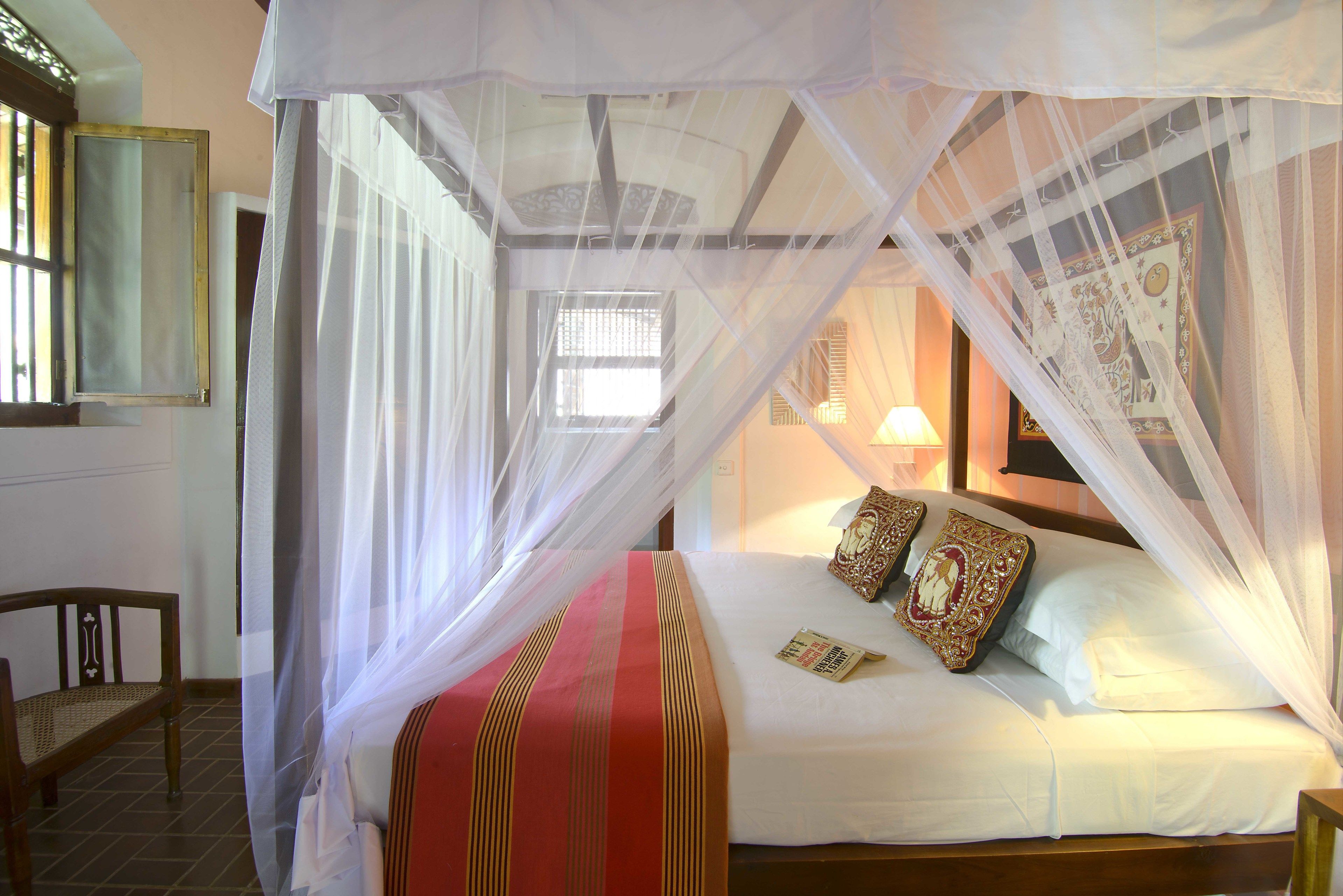 A bed with a canopy, a bedside table, and a chair.