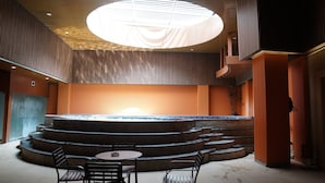 Een modern interieur met een rond podium, trappen en een groot dakraam.