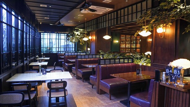 Een restaurantinterieur met zitjes, tafels en een boekenplank.
