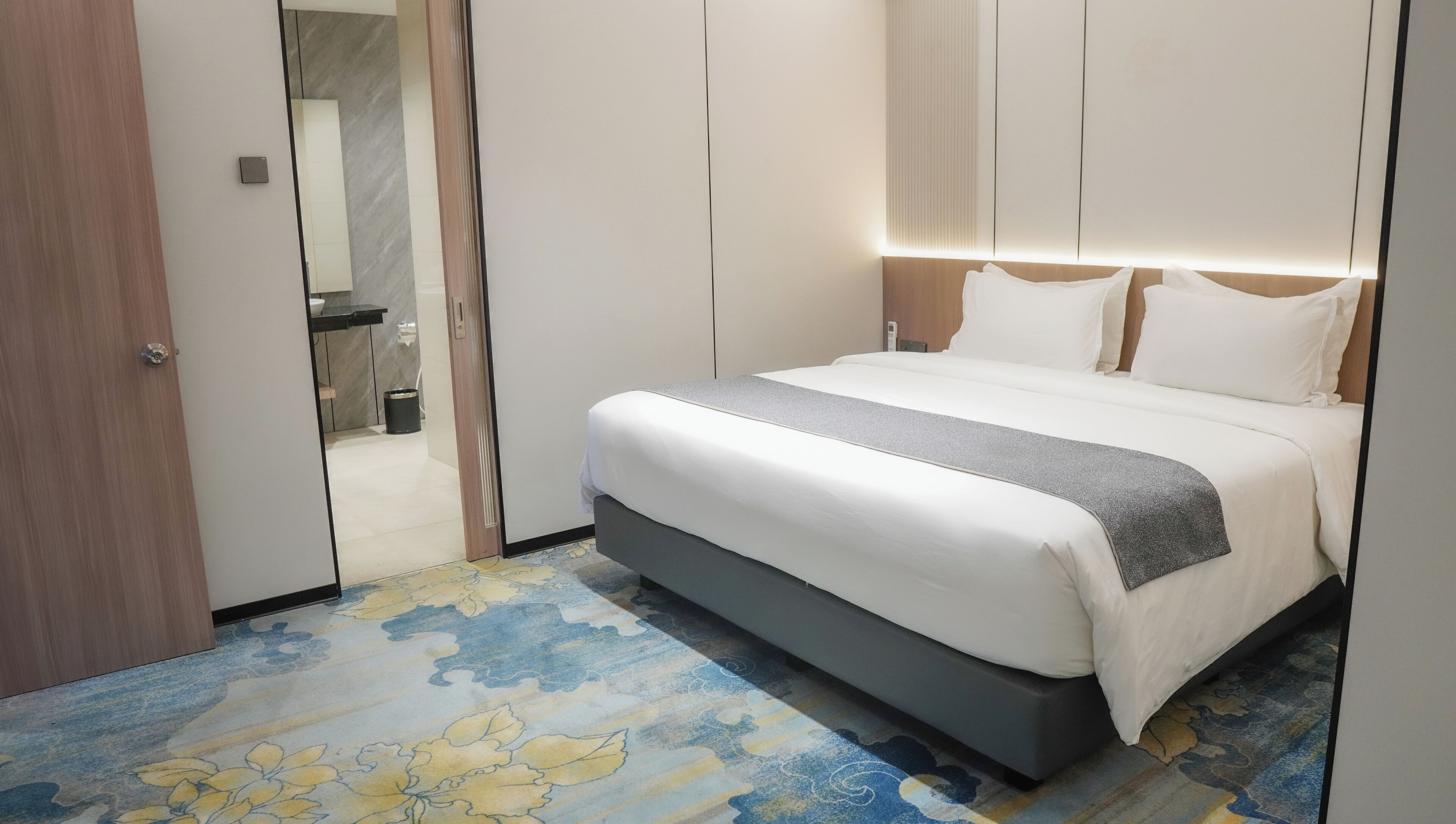 Una habitación de hotel con una cama, baño y puerta.