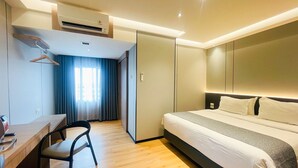 Een moderne hotelkamer met een bed, bureau, stoel en een airconditioning.