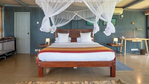 Ein Schlafzimmer mit einem großen Bett, einem Holz-Kopfteil, einem Nachttisch mit Lampe sowie einem kleinen Tisch ebenfalls mit Lampe.