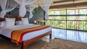 Ein Schlafzimmer mit einem großen Bett, einem weißen Baldachin und Blick ins Freie vom Balkon.