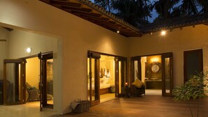 Un espacio exterior bien iluminado con suelo de madera, puertas de vidrio que dan a un dormitorio, una zona de estar y un baño.