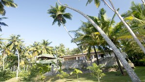 Un resort tropical con palmeras, un muro de piedra y un edificio con techo de tejas.