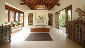 Un dormitorio amplio con una cama grande, vigas de madera en el techo y una estatua decorativa de un caballo.