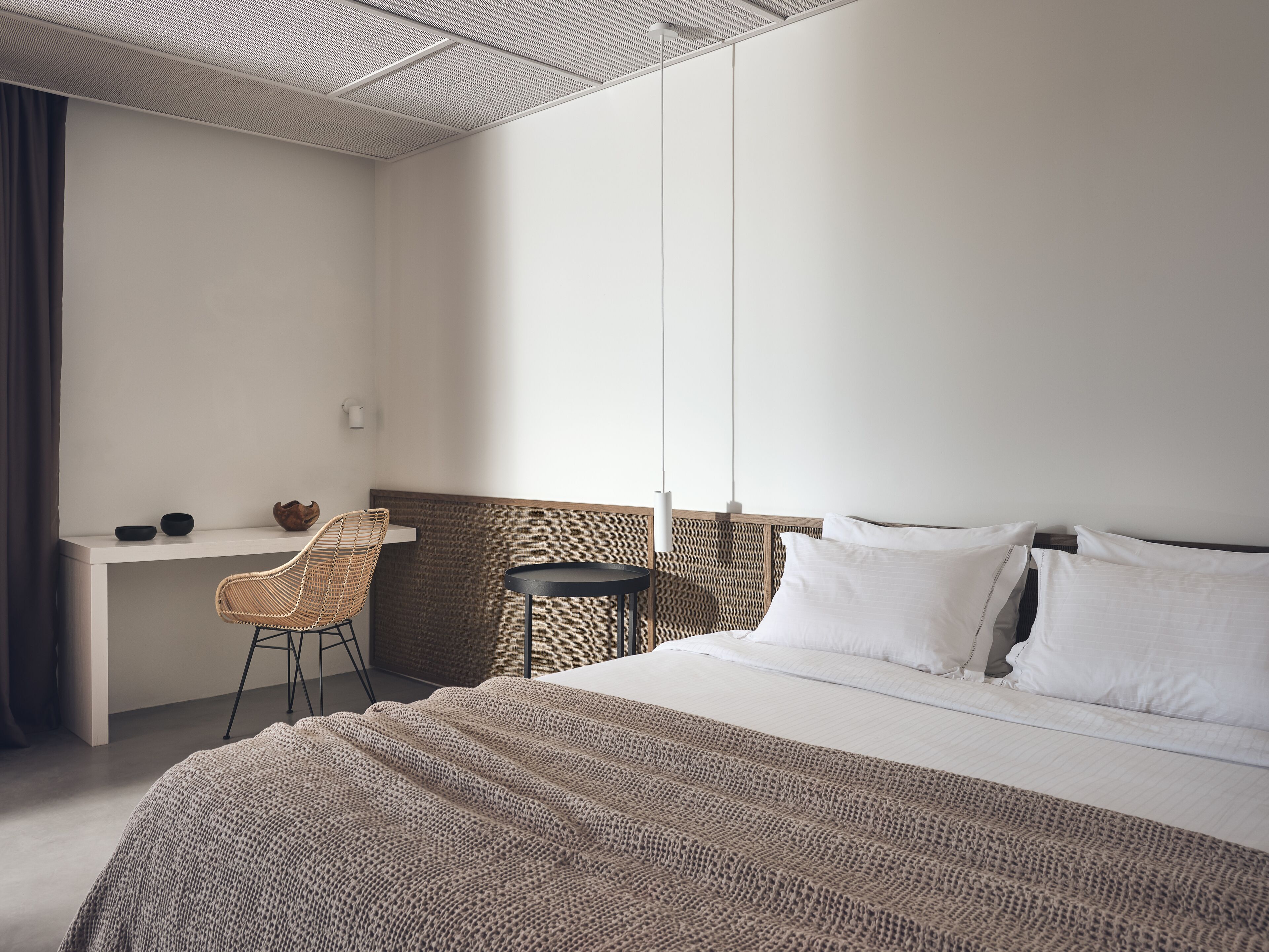 A hotel room with a bed, a desk, a chair, and a window.