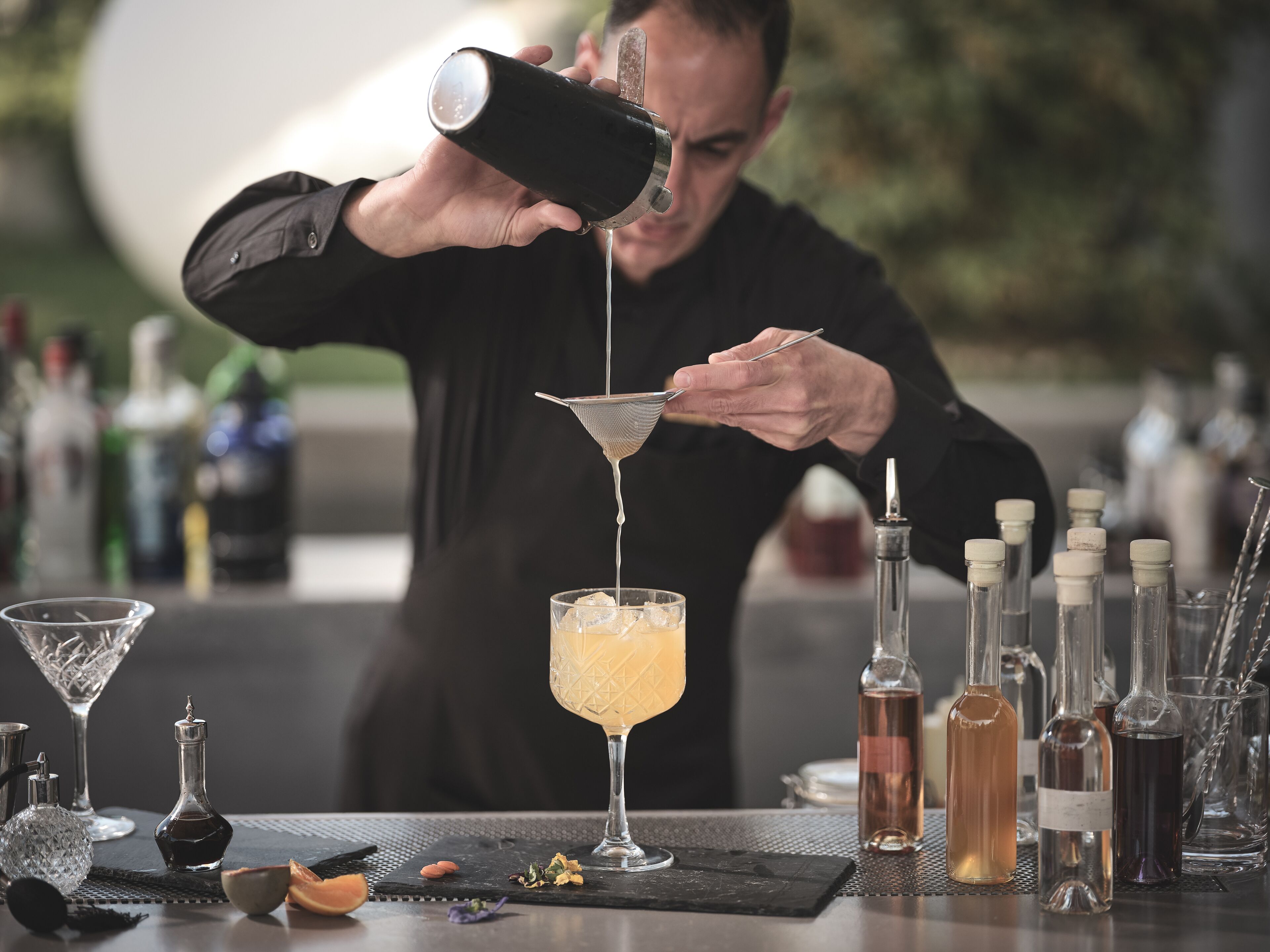 A bartender pouring a drink into a martini glass.