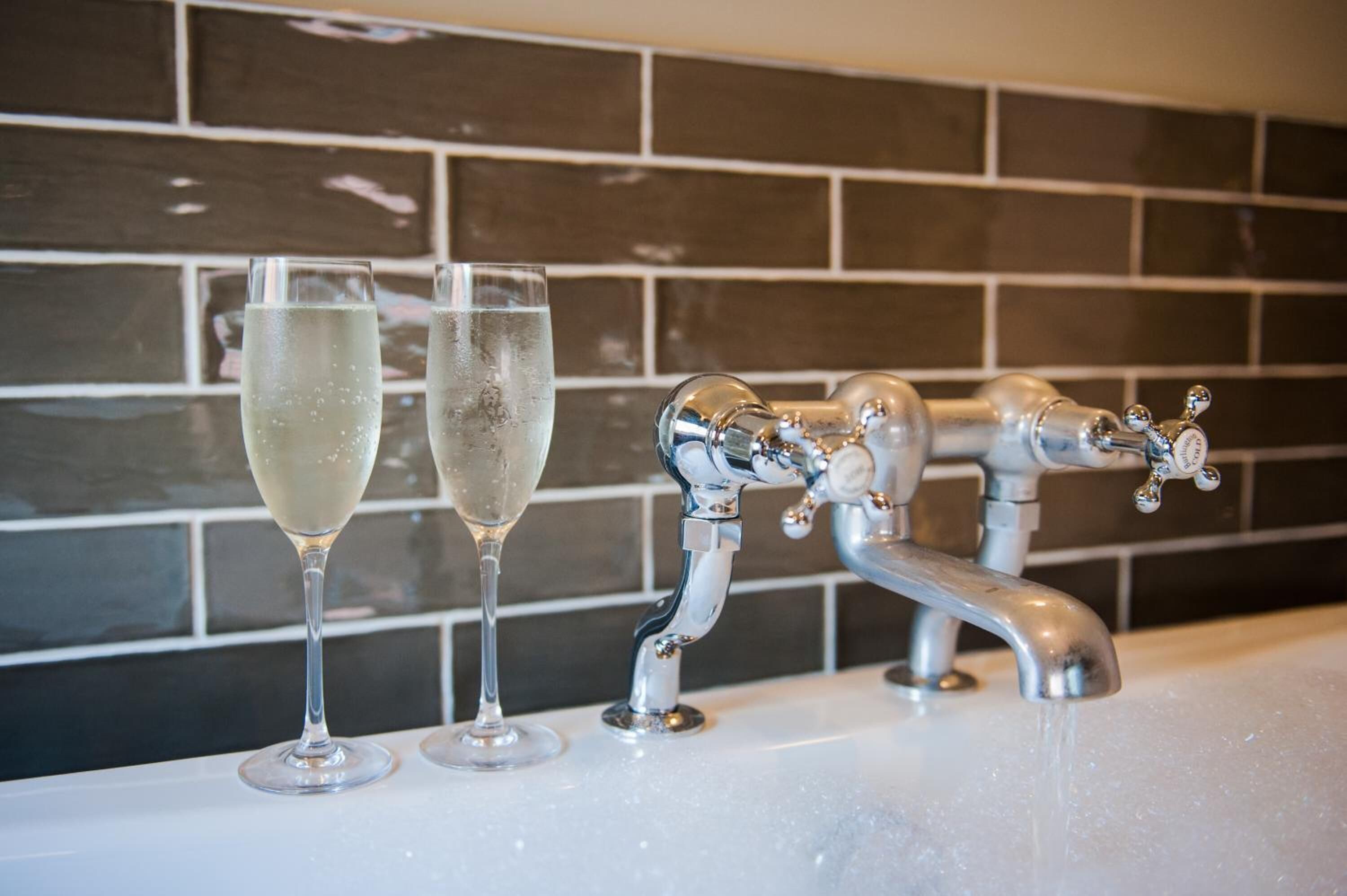 A bathroom with a modern faucet and two glasses of water on the sink.