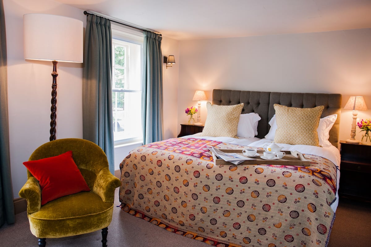 A neatly arranged hotel room with a bed, a chair, and a bedside table.