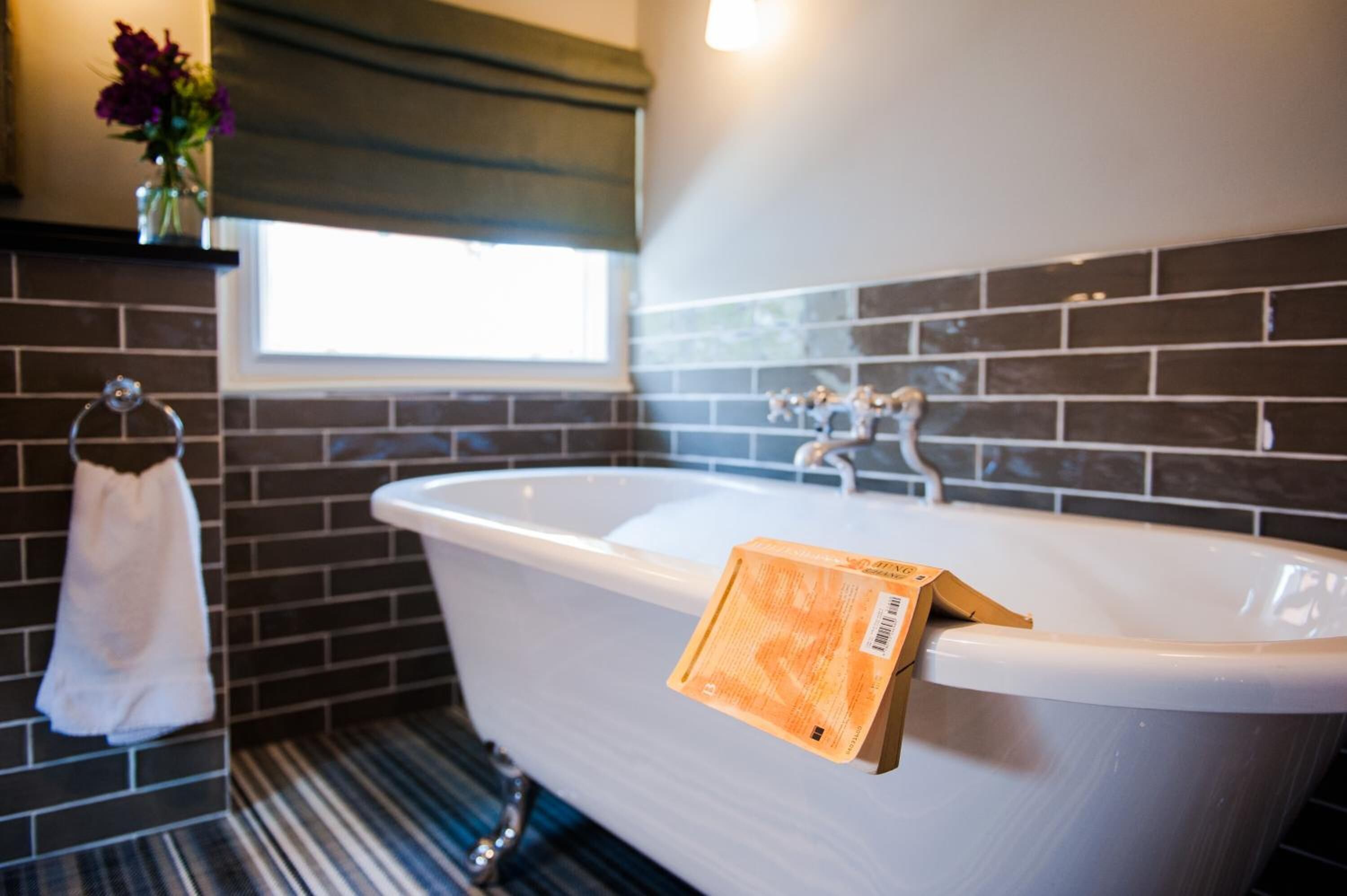A bathroom with a freestanding bathtub, a towel rack with a white towel, and a window with a view of the outside.