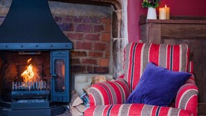 A cozy room with a fireplace, a striped armchair, and a vase with flowers.