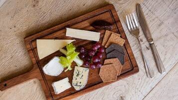 Una tabla de madera con varios quesos, uvas y galletas.