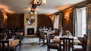 A dining area with wooden furniture, a fireplace, and a chandelier.
