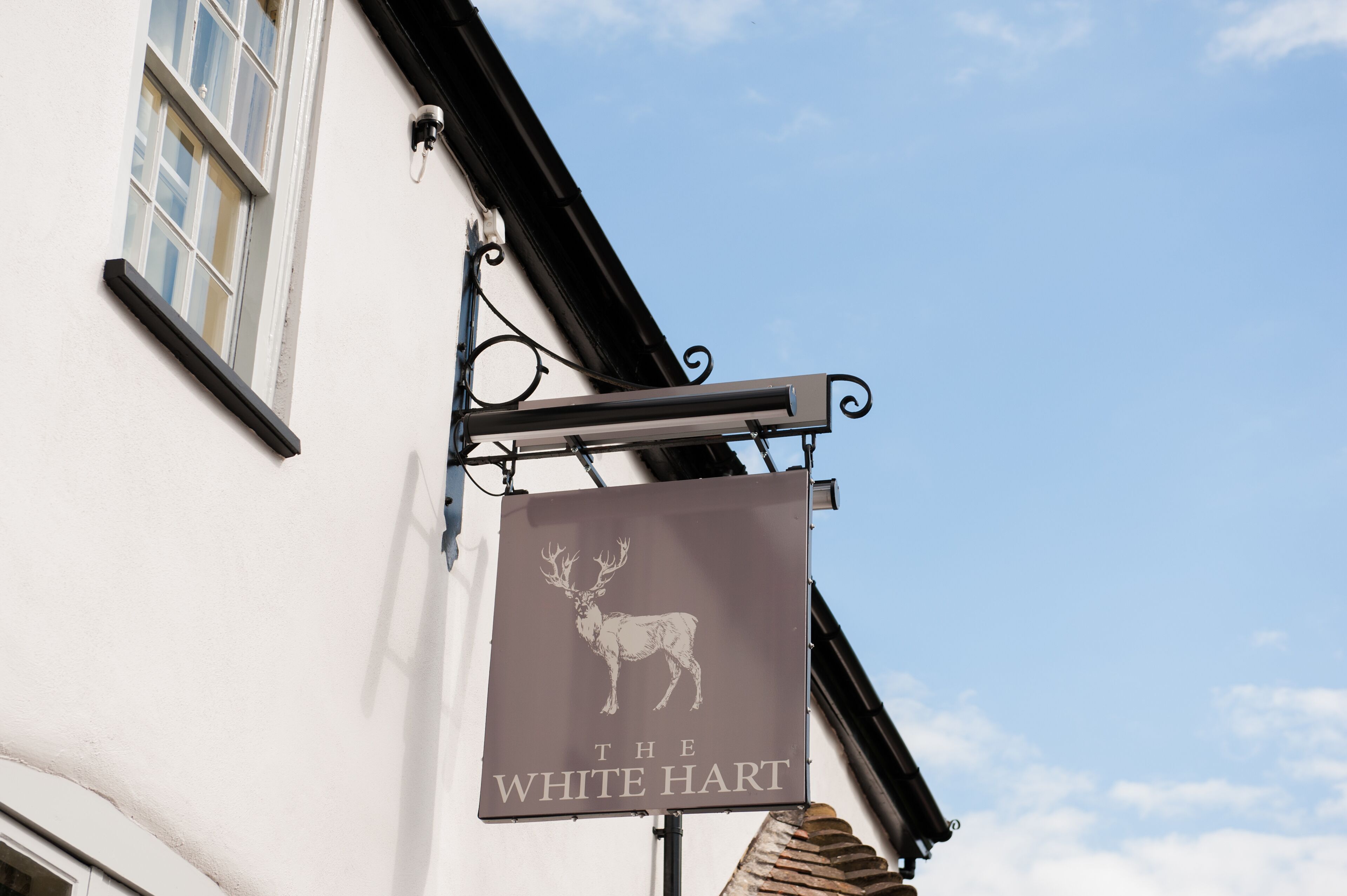 Um edifício com uma placa que diz "The White Hart" e a imagem de um veado.