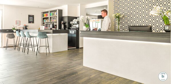 Un espace bar moderne comprenant un comptoir, des tabourets de bar et une machine à café.