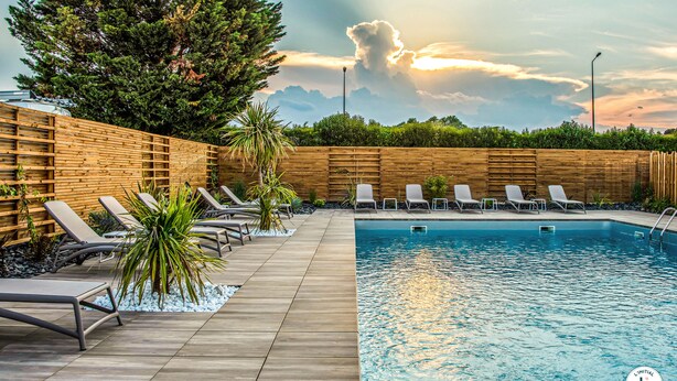 Un área de piscina con sillones de descanso y una cerca de madera.