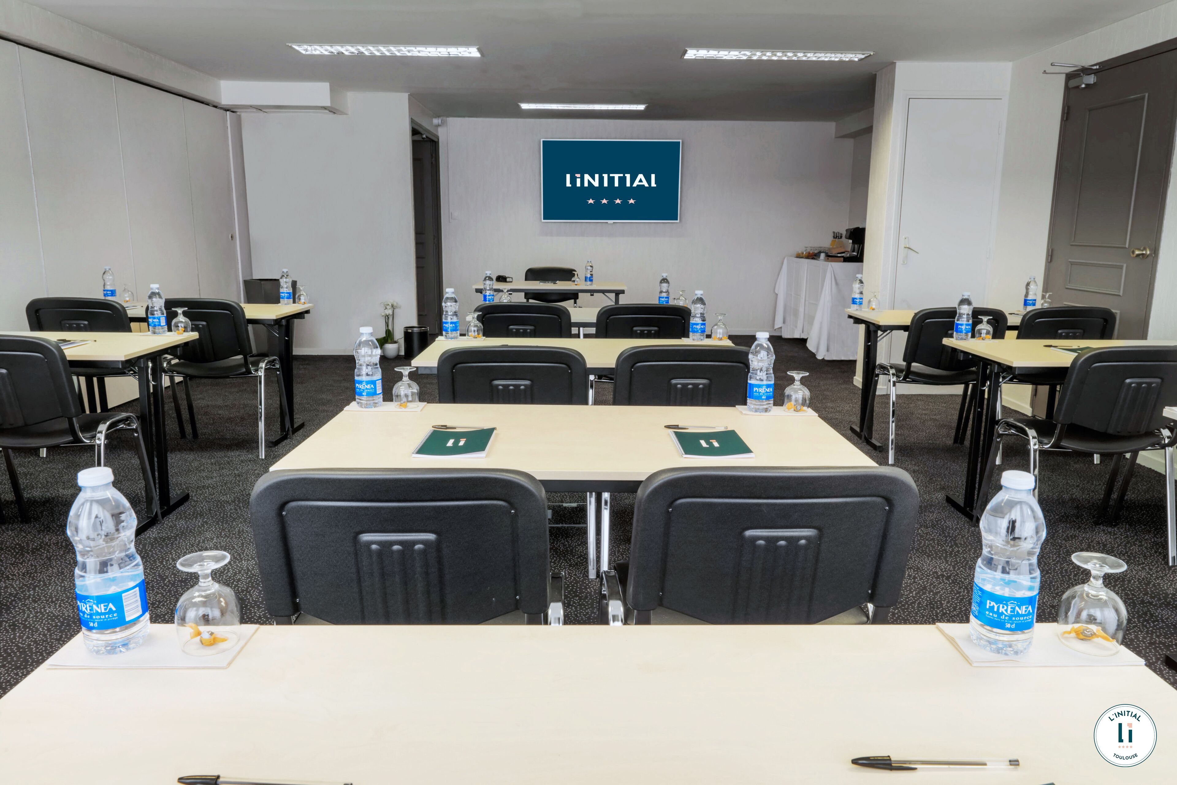 A conference room with tables, chairs, water bottles, and a sign on the wall.