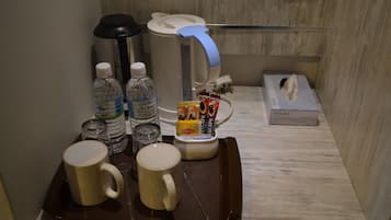 Hotelkamer met koffiehoek, inclusief koffiezetapparaat, waterflesjes en een dienblad met twee mokken.