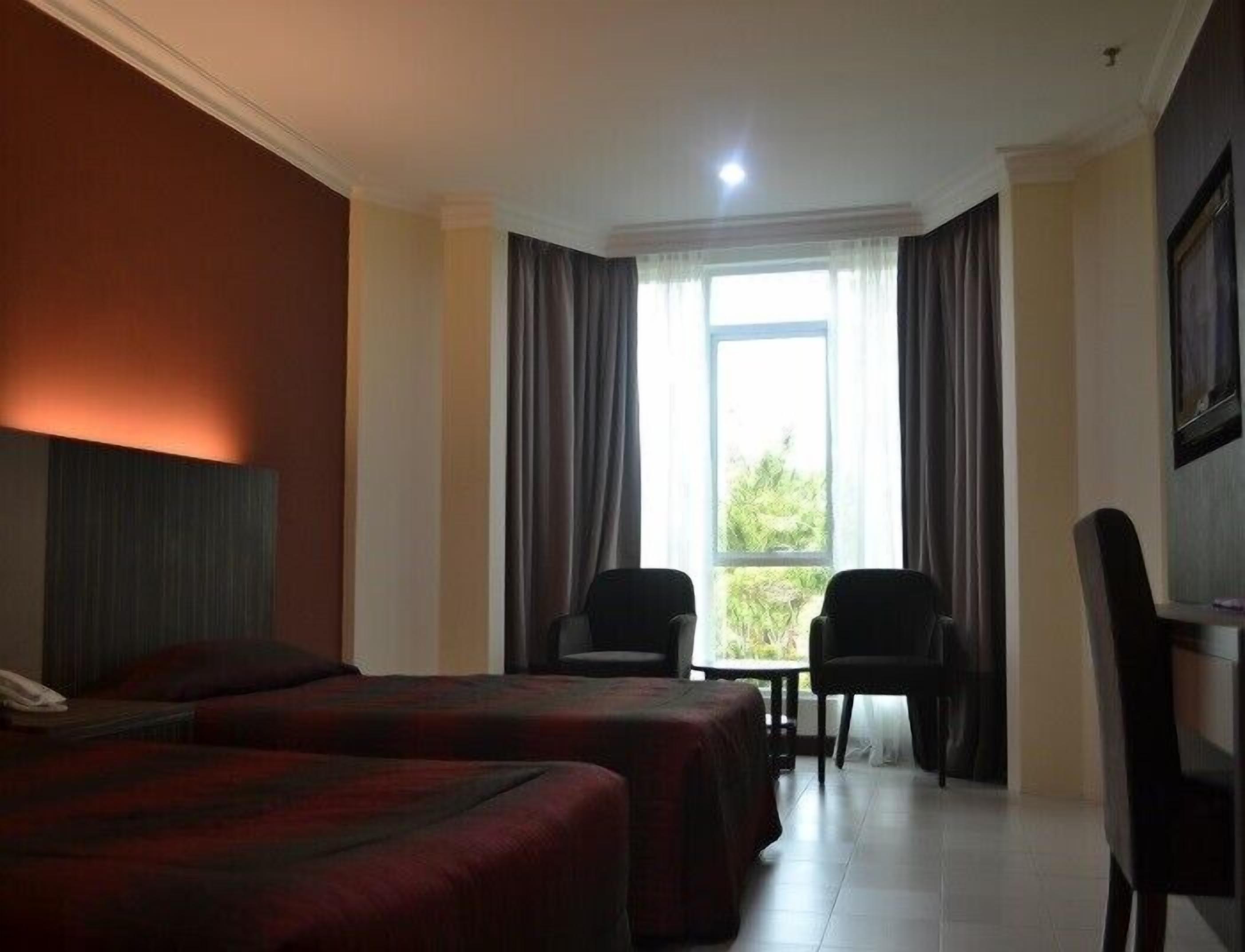 A hotel room with two beds, a desk, and a chair.