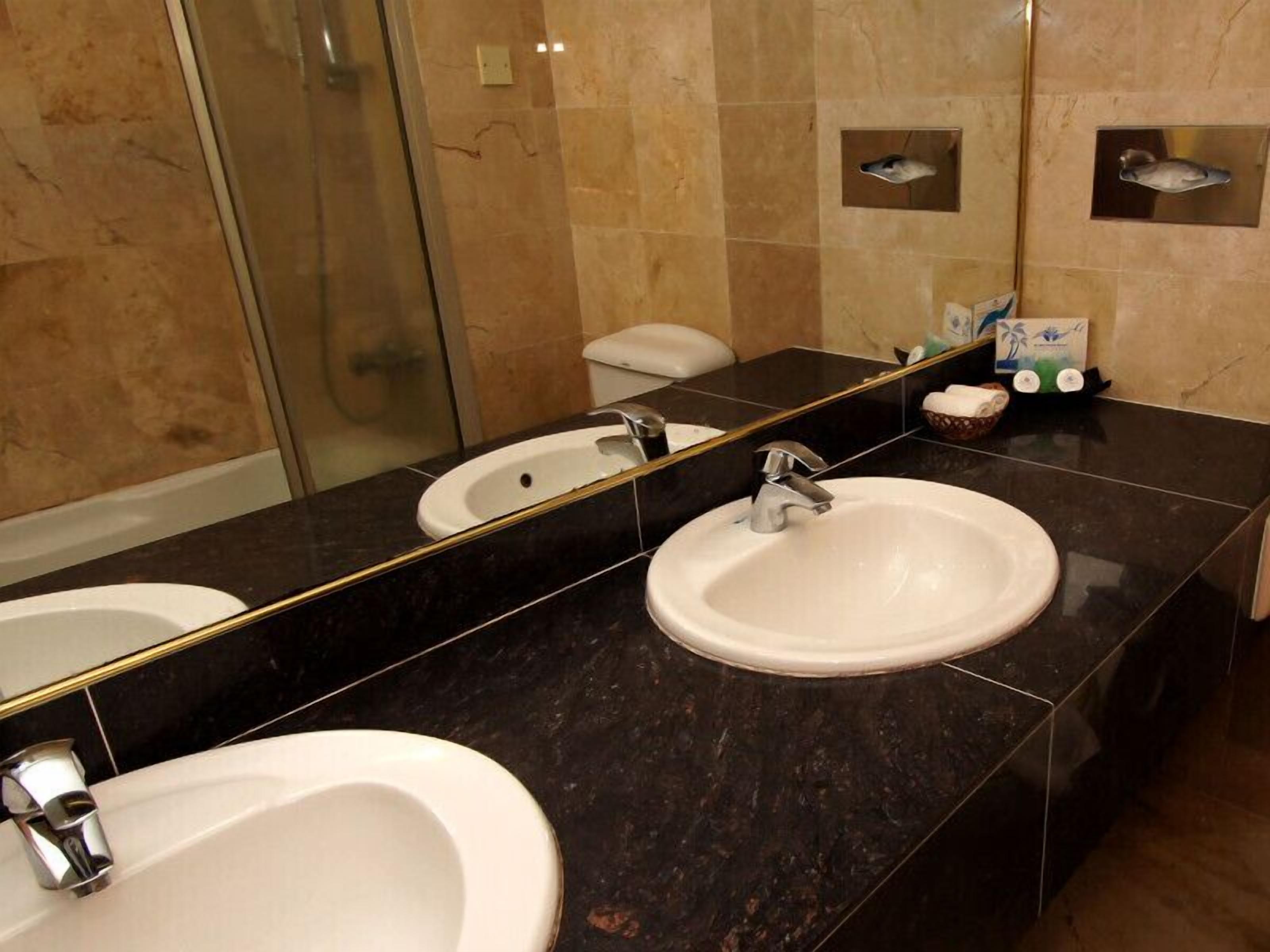 A bathroom with two sinks, a large mirror, and a shower area.