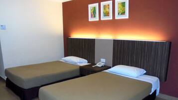A hotel room with two single beds, a bedside table with a phone, and a wall with three framed pictures.