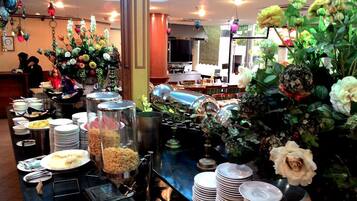 A buffet setup with various food items and a decorative floral arrangement.