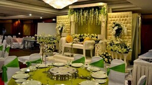 A banquet hall with round tables, white chairs, and a central stage with floral decorations. - De Rhu Beach Resort (Kuantan)