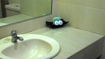 A bathroom with a white sink, a mirror, and a soap dish with two bottles.