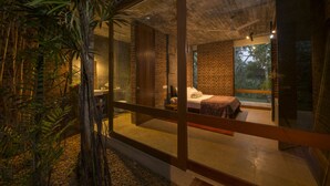 Een moderne slaapkamer met een groot raam, een bed en een badkamer zichtbaar door glazen deuren.