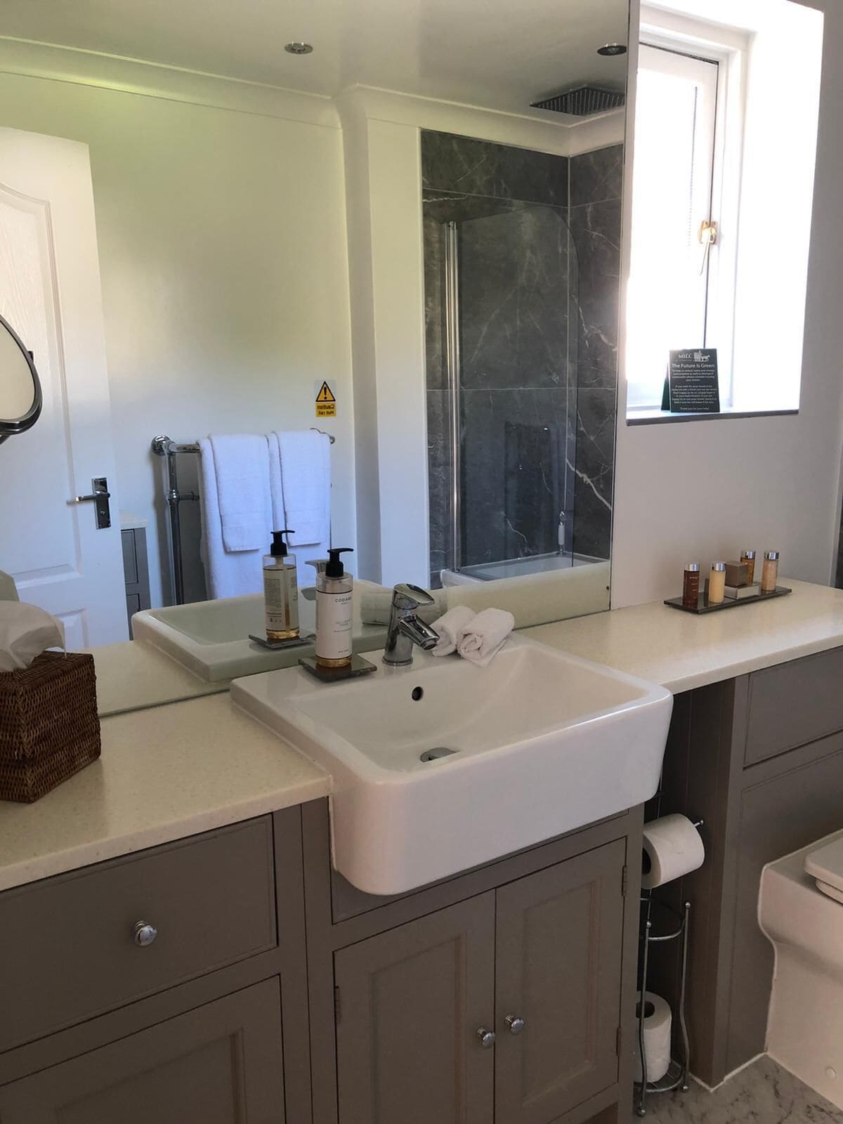Ein modernes Badezimmer mit einem großen Spiegel, zwei Waschbecken, einer Dusche und einer Toilette.