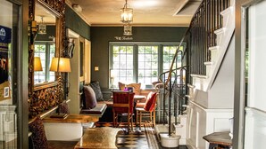A hallway with a checkered floor leading to a staircase, a bench, and a table with chairs. - The Old Mill (Lymington)