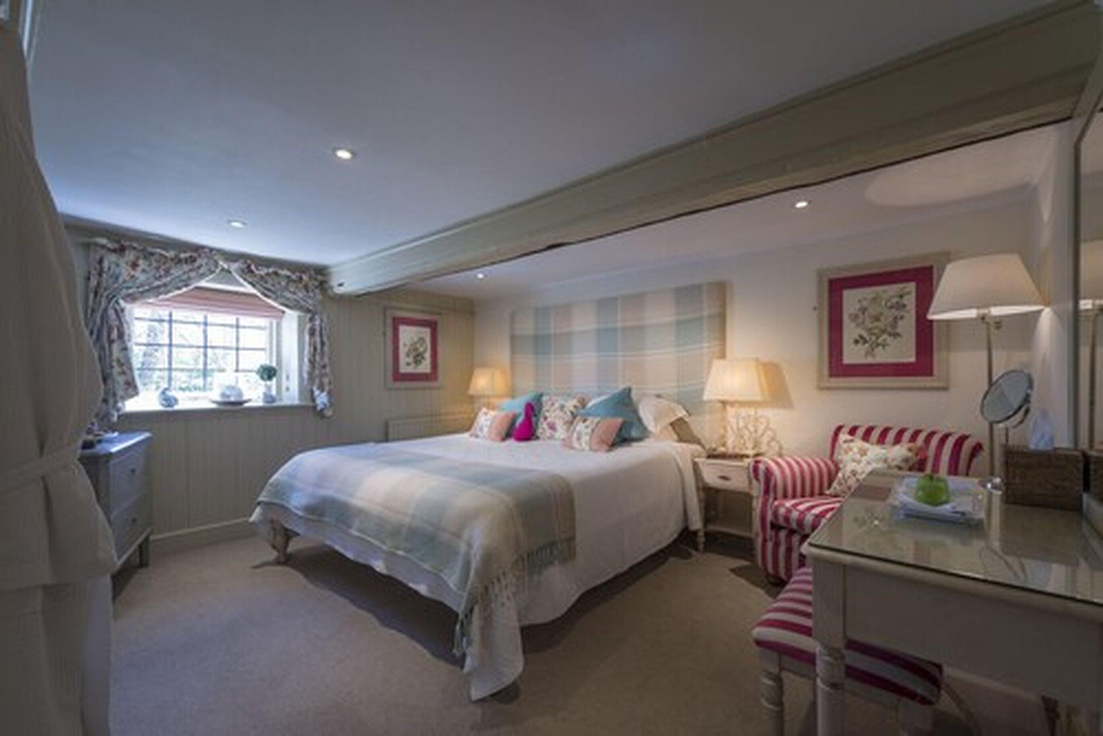 A bedroom with a bed, bedside tables, a chair, and a window.