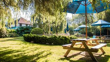 Un jardín con mesas de picnic y sombrillas azules.