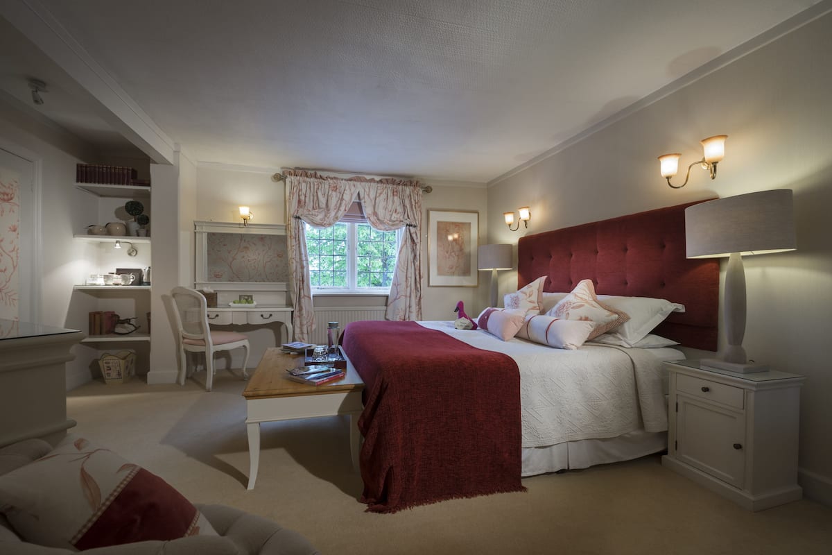 A bedroom with a bed, bedside tables, a desk, and a chair.