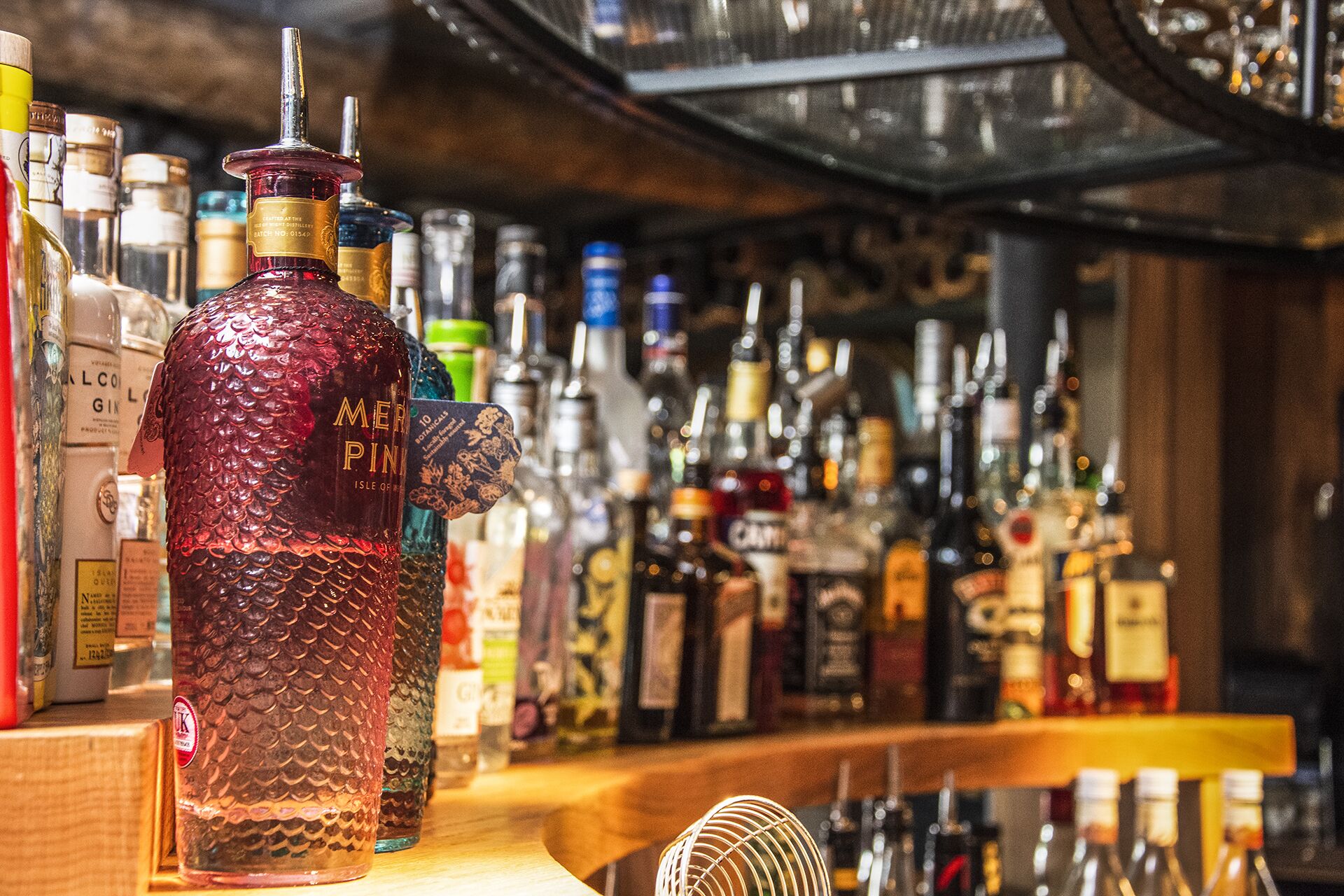 A bar with a variety of liquor bottles, including a prominent bottle labeled "MER PINK".