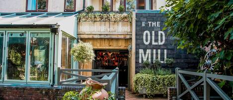 En pittoresk byggnad med en skylt som visar texten ”RIVERSIDE PUB WITH ROOMS” och en annan skylt med texten ”THE OLD MILL”.