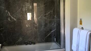 Un baño moderno con pared de mármol, una bañera independiente y un inodoro.