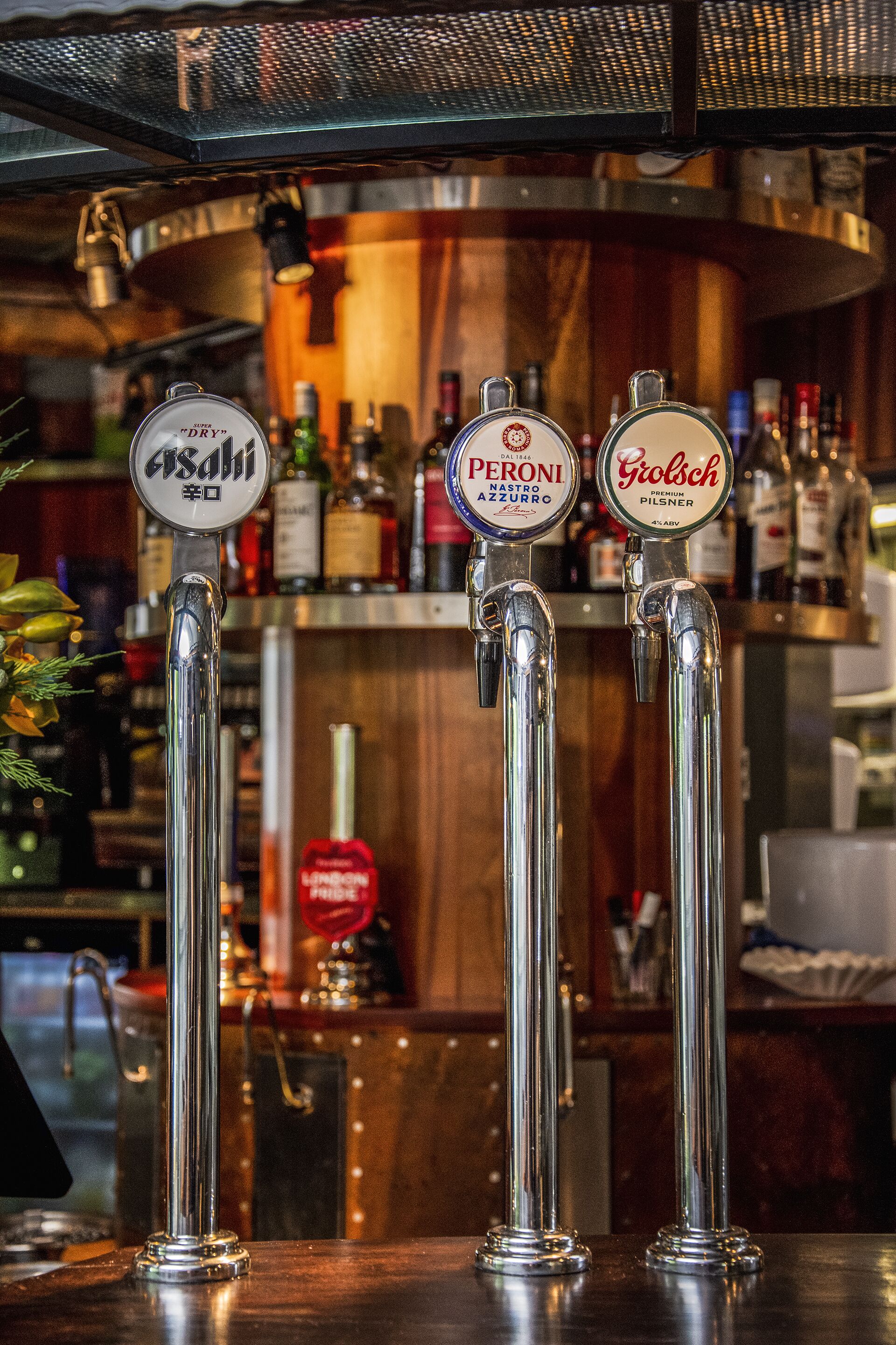Tres grifos de cerveza con marcas como Asahi, Peroni y Grolsch.