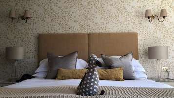 Una cama bien hecha con cabecera, dos lámparas de noche y un cojín estampado de lunares.