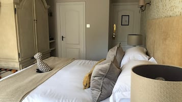 Ein ordentlich eingerichtetes Hotelzimmer mit einem großen Bett, einem Kleiderschrank, einer Lampe und einer Wandleuchte.